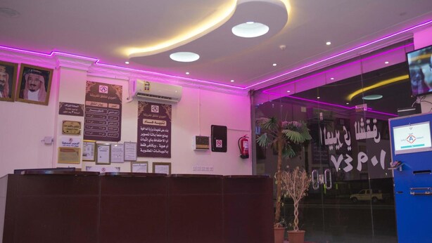 A reception area with a reception desk, framed certificates, and a digital screen.