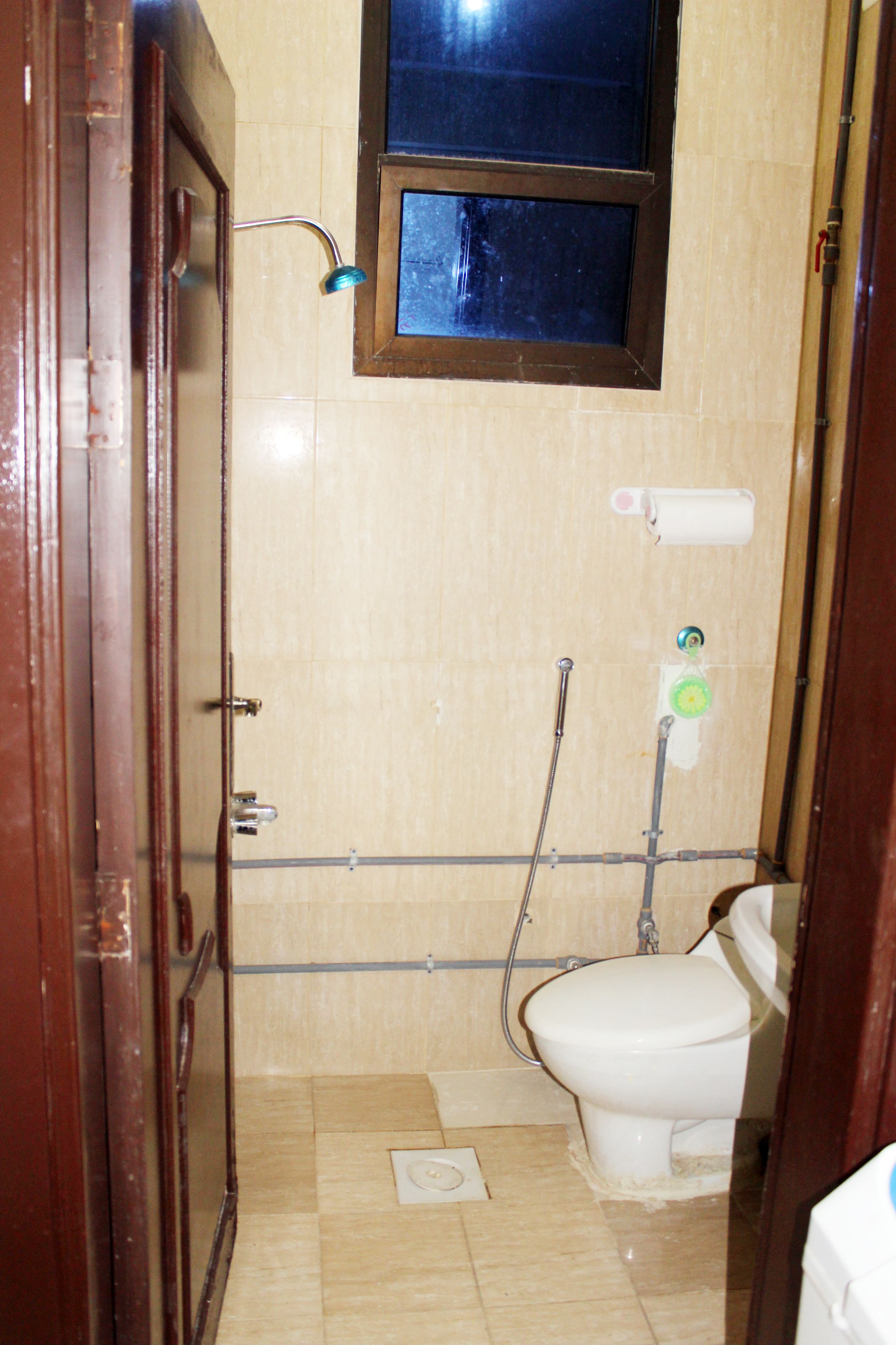 Un baño pequeño con azulejos, un inodoro, una ducha y una ventana.