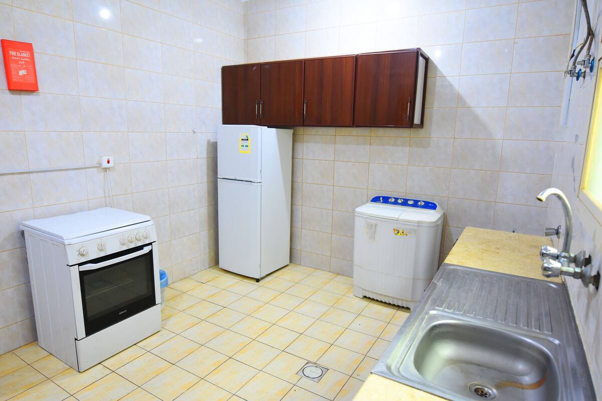 Una cocina compacta con estufa, refrigerador y lavaplatos.