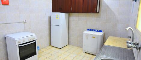 A compact kitchen with a stove, refrigerator, and sink.