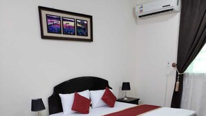 Een netjes ingerichte slaapkamer met een bed, twee nachtkastjes met lampen, een groot decoratief vloerkleed en een lijst met een afbeelding aan de muur.