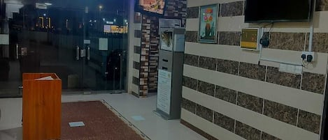 Un área de recepción con mostrador, televisor montado en la pared y alfombra estampada.