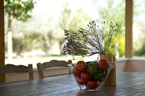 A clear glass bowl with tomatoes and a sprig of herbs on a wooden table. - Agrotospita Country Houses (Nafplio)