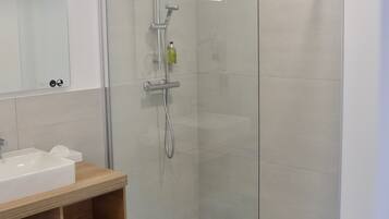A modern bathroom with a glass-enclosed shower, a wooden vanity, and a white sink.