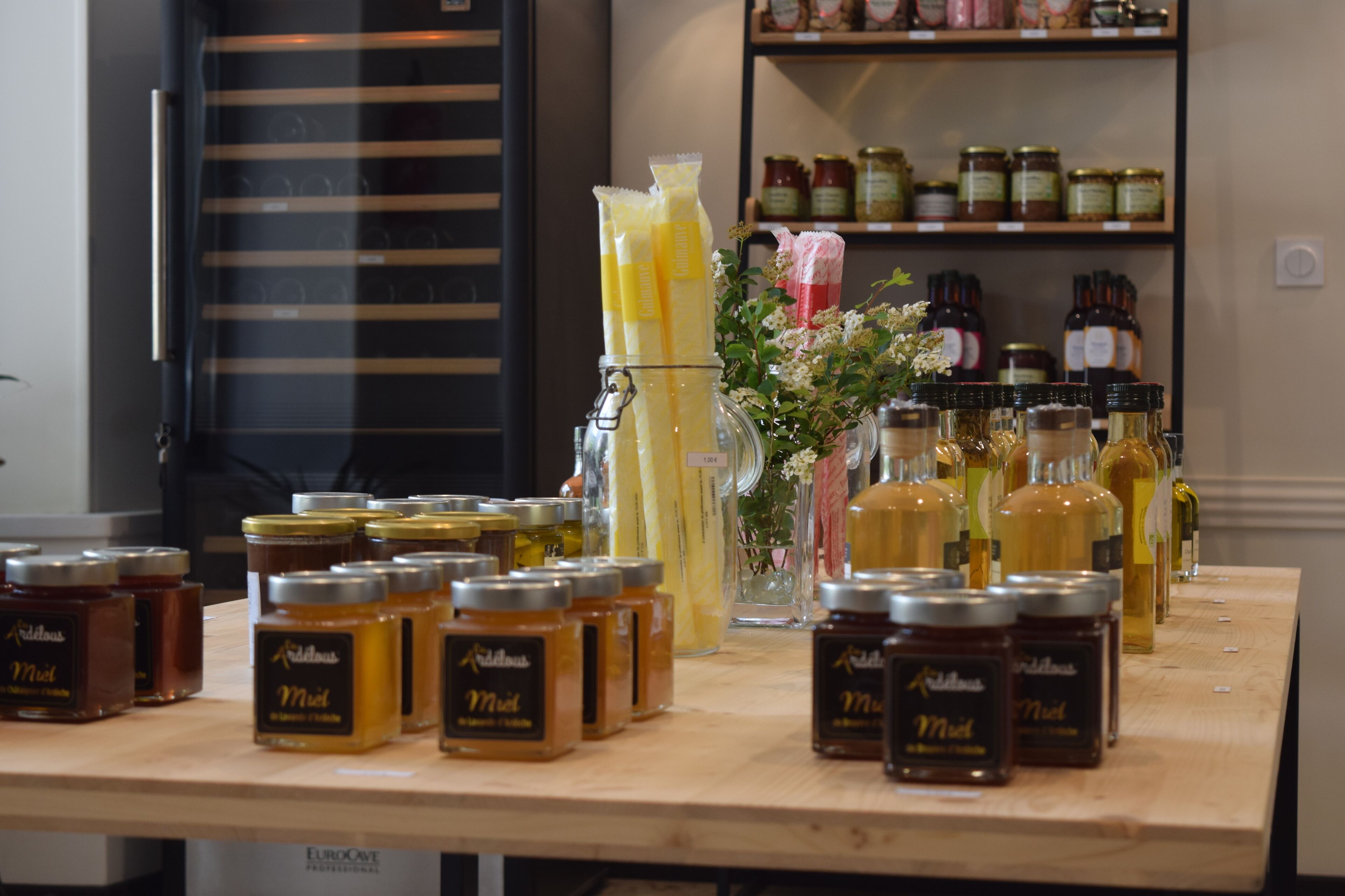 Una exhibición de frascos y botellas de miel sobre una mesa de madera.