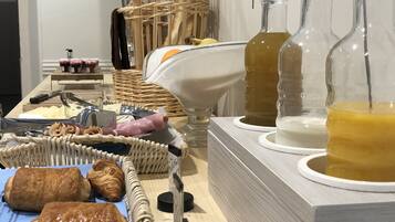 A breakfast buffet with pastries, a wicker basket, and glass decanters of beverages.