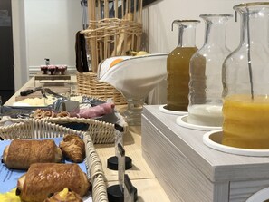 A breakfast buffet with pastries, a wicker basket, and glass decanters of beverages. - Hôtel et Appartements Les Platanes (Thueyts)