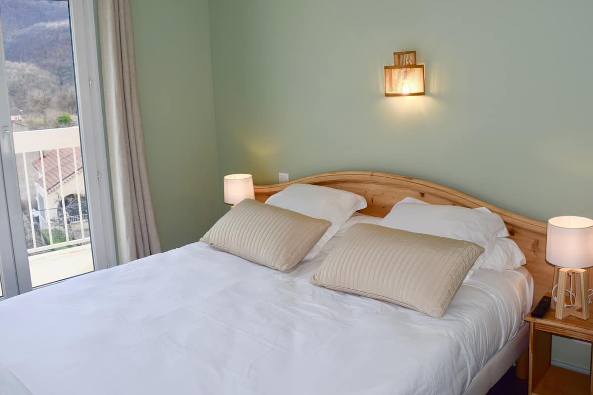 Un lit bien fait, avec deux oreillers, une tête de lit en bois et des lampes de chevet.