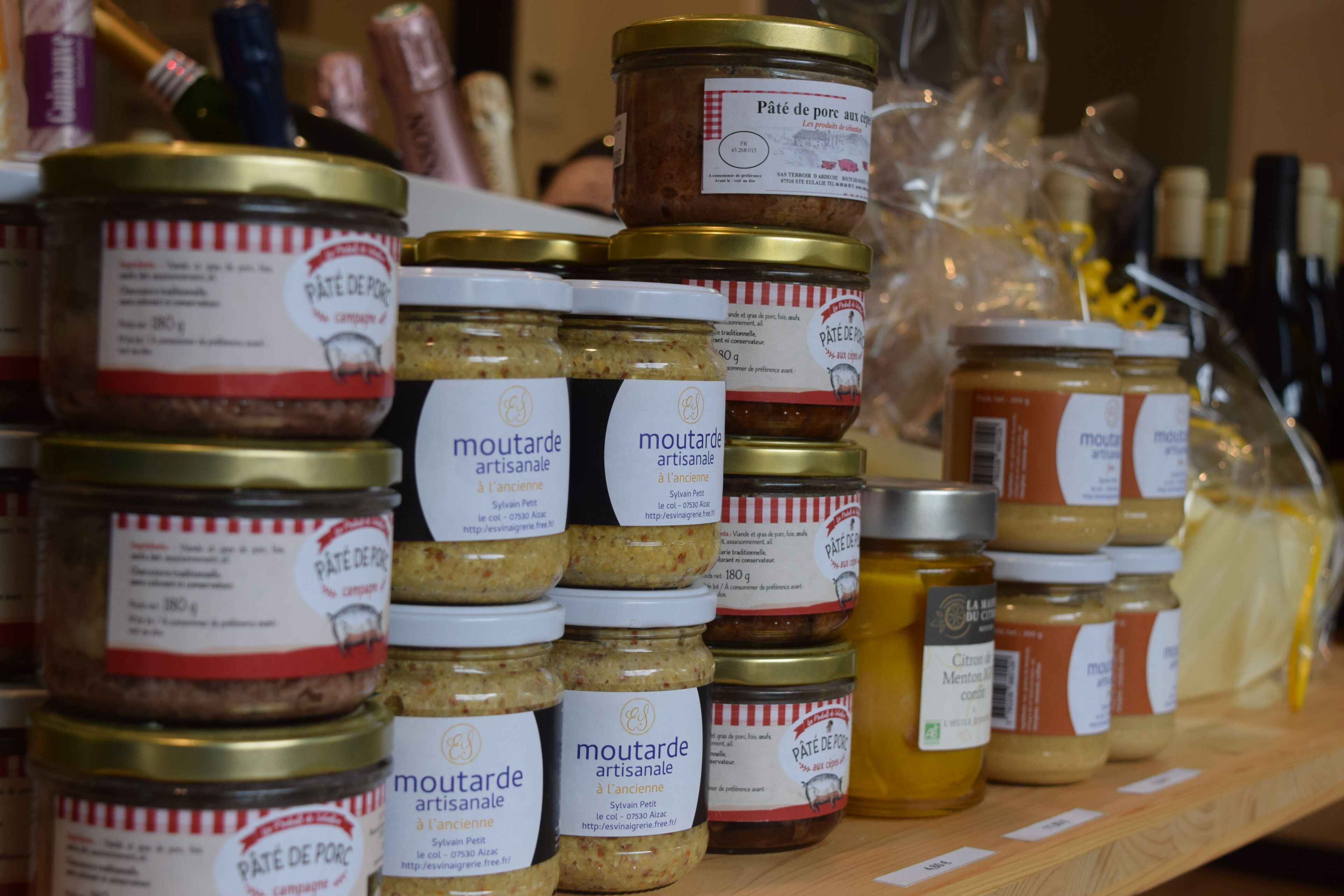 A shelf with various jars of pâté de foie gras and mustard.
