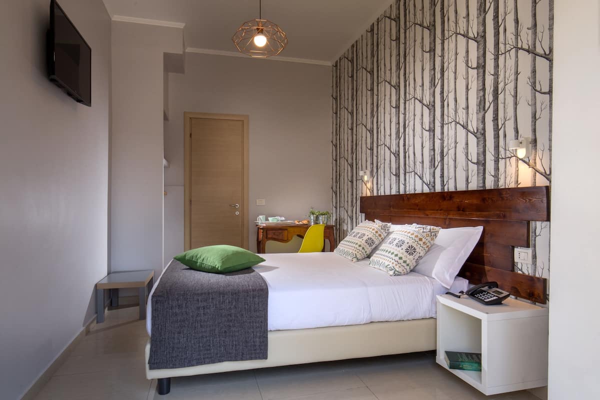 A modern bedroom with a bed, bedside table, and a wall-mounted TV.