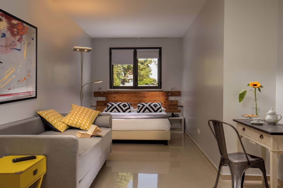 A modern bedroom with a bed, a sofa, a desk, and a chair.