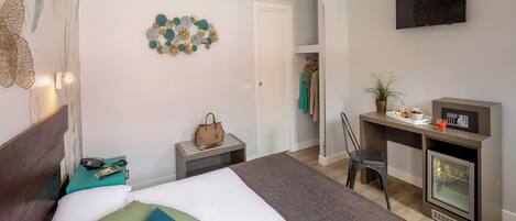 Una habitación de hotel con cama, escritorio, silla, televisor y minibar.