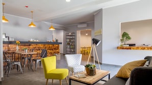 A modern living room with a wooden dining table, yellow and patterned chairs, a sofa, and a floor lamp. - Urban Garden Hotel (Rome)