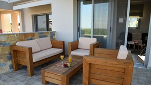 A patio area with wooden furniture, including a sofa and chairs, and a coffee table with fruits and a drink. - Edem Suites (Trifylia)