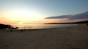 A beach at sunset with a clear sky, calm sea, and a few people on the sand. - Edem Suites (Trifylia)