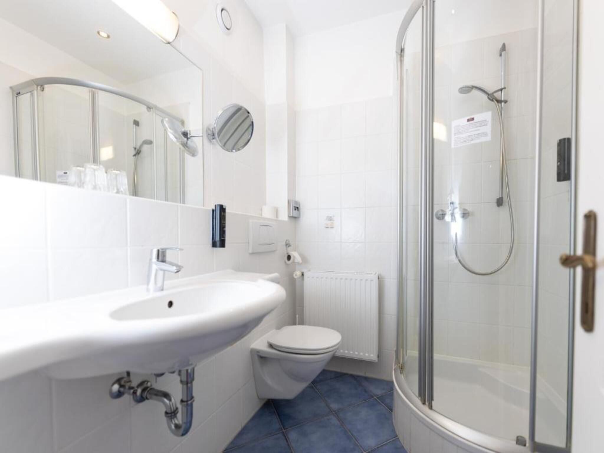 A modern bathroom with a white sink, toilet, and glass-enclosed shower.