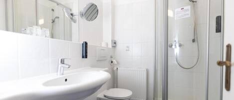 A modern bathroom with a white sink, toilet, and glass-enclosed shower.