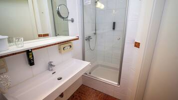 A bathroom with a white sink, a mirror, a shower, and a toilet.