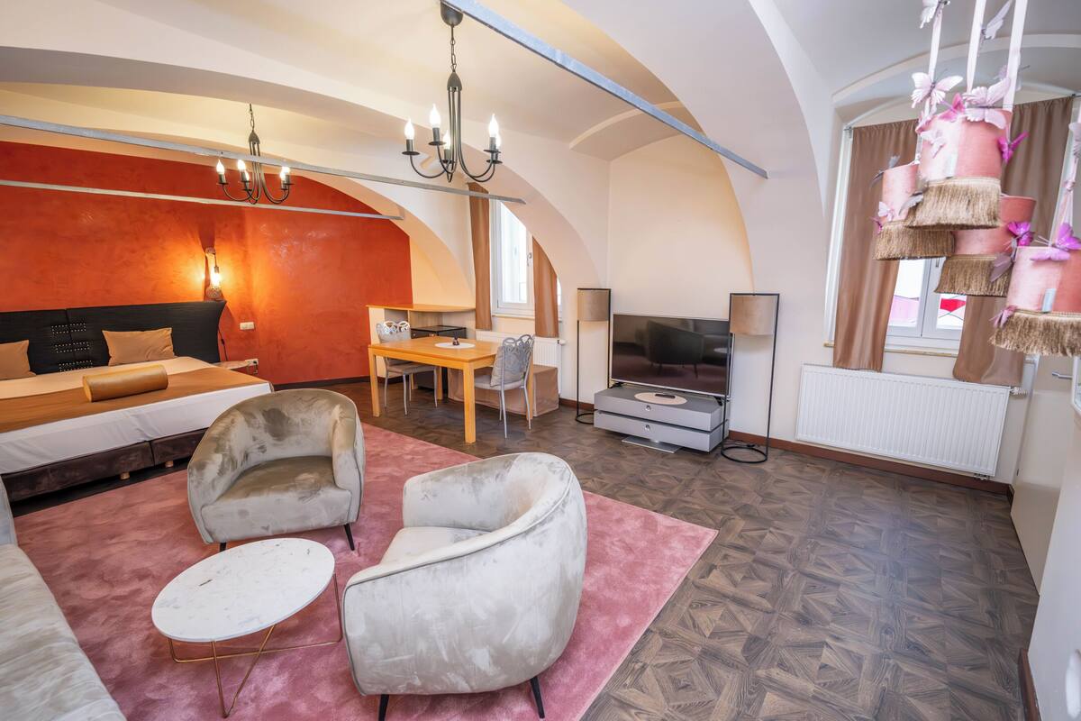 Una sala de estar moderna con un sofá, sillones, una mesa de comedor y un televisor.