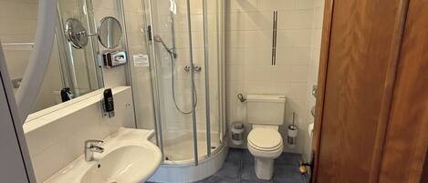 A modern bathroom with a glass shower enclosure, a white toilet, and a sink with a mirror.