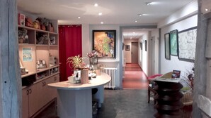 A hotel lobby with a central round table, a red curtain, and a hallway leading to another room. - Hôtel Fouillade (Argentat-sur-Dordogne)