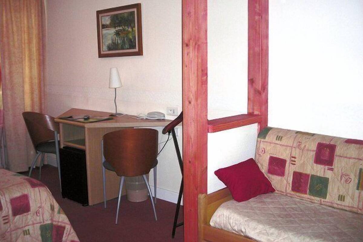 A room with a bed, a desk, a chair, and a window.