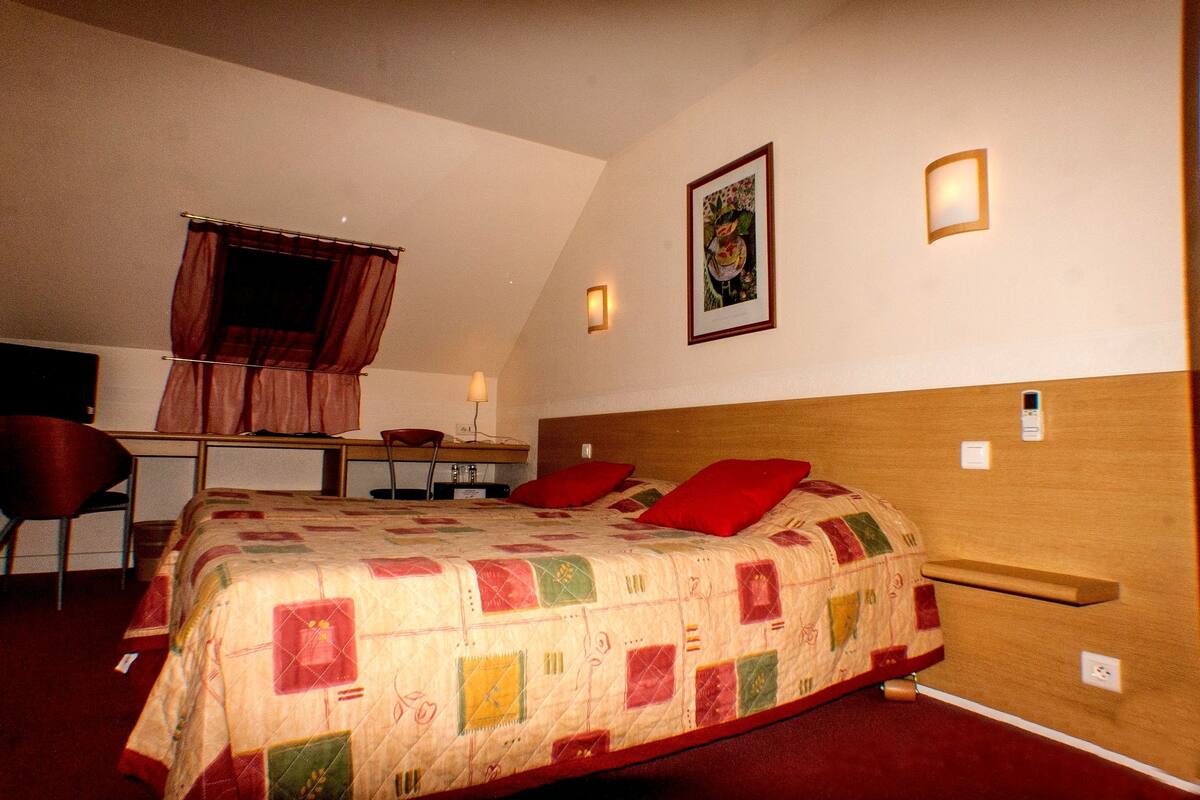 A hotel room with a bed, a desk, and a chair.
