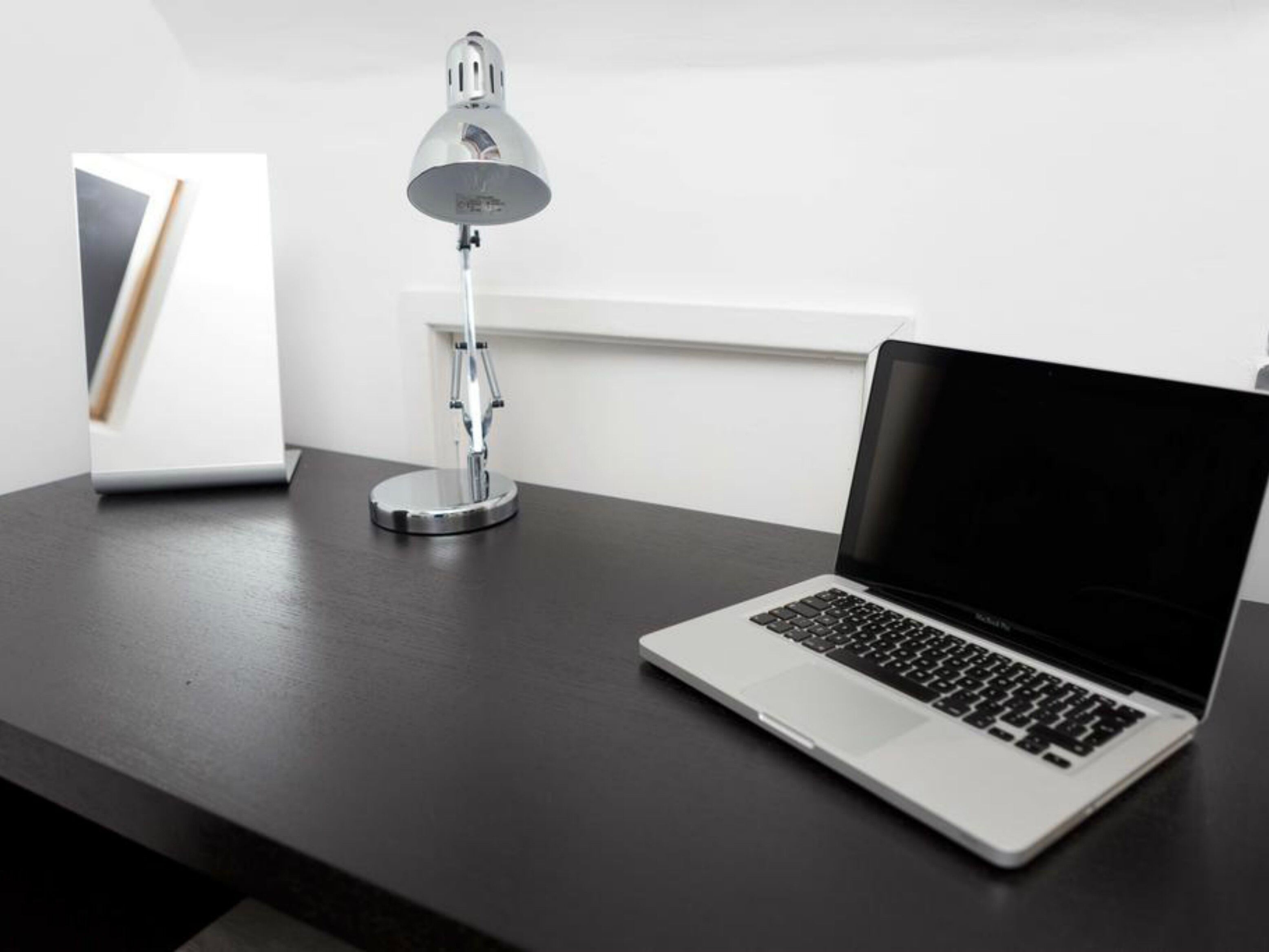 Un ordinateur portable sur un bureau sombre, éclairé par une lampe de bureau moderne.