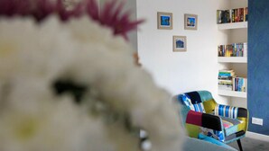 En stue med en sofa, en bogreol og billeder i rammer på væggen.