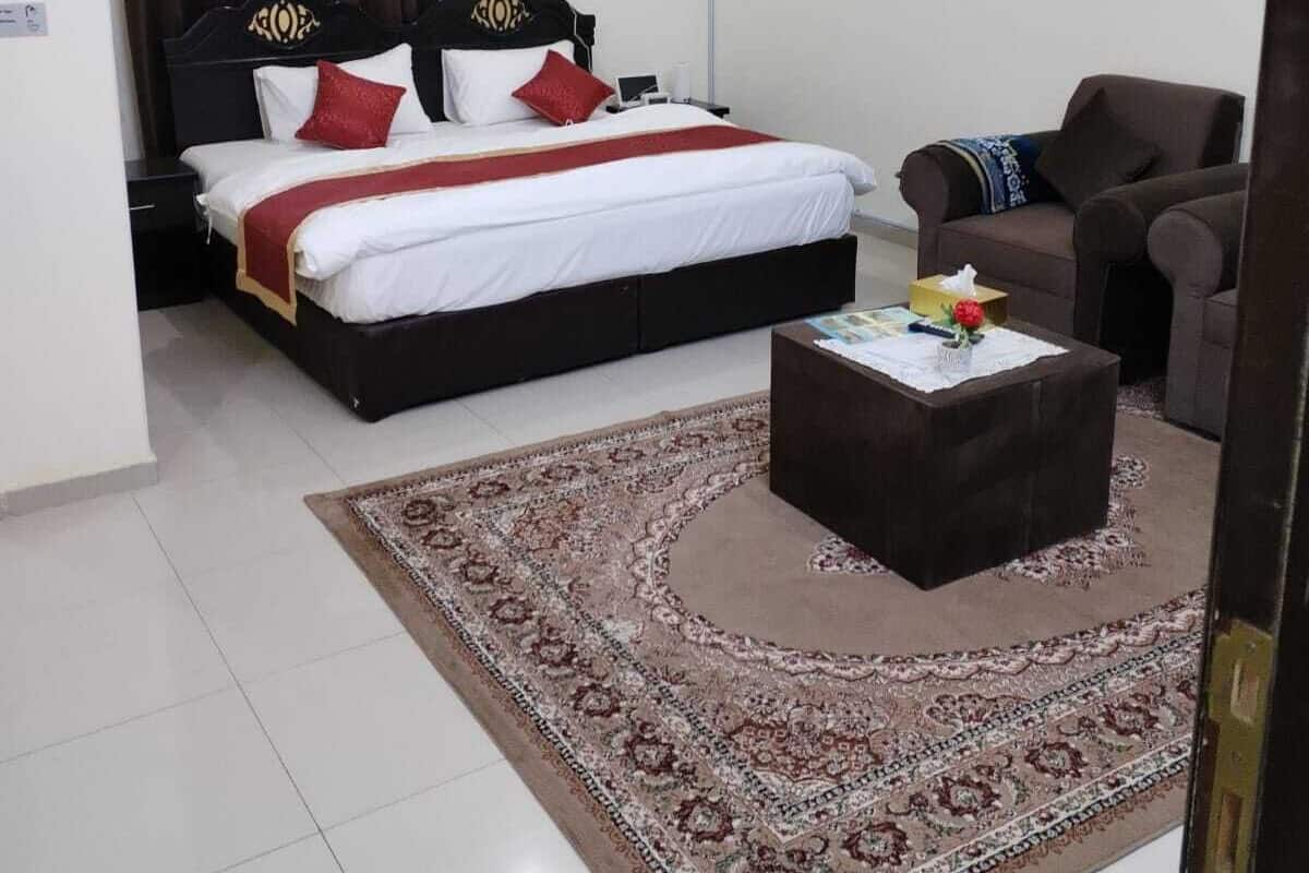 Quarto com cama, cadeira, mesa de centro e tapete.