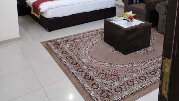 A hotel room with a bed, a sofa, a coffee table, and a rug.