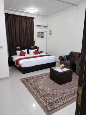 A hotel room with a bed, a sofa, a coffee table, and a rug. - Al Eairy Serviced Apartments Company 4 (Ha'il)