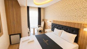 Una habitación de hotel con cama, una mesita, una silla, un armario y un escritorio.