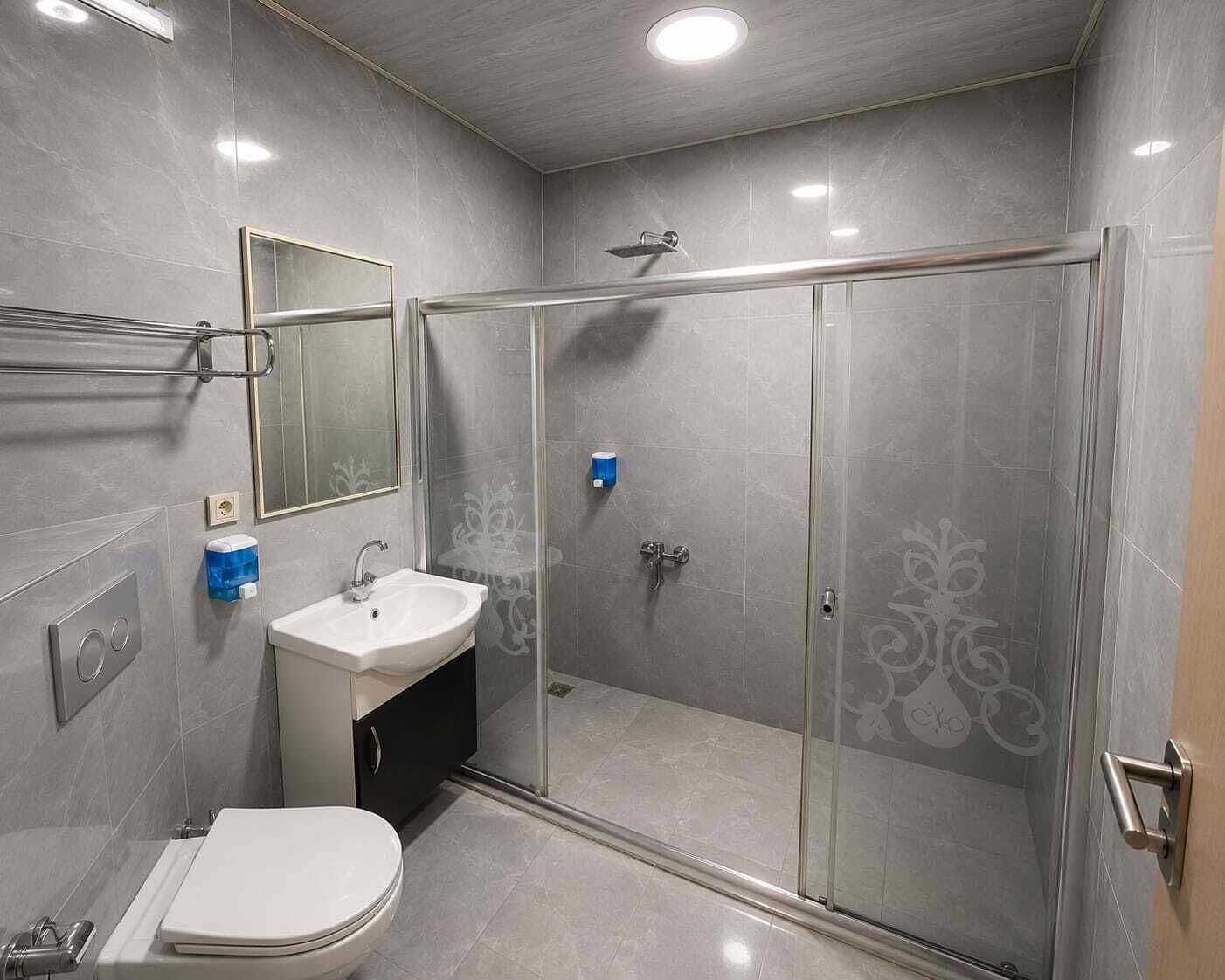 A modern bathroom with a toilet, sink, and glass-enclosed shower stall.