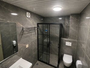 A modern bathroom with a glass-enclosed shower, a white bathtub, and a toilet. - Grand Mardini Hotel (Mersin)