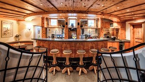 A bar area with wooden stools, a bar counter, and a wooden ceiling.