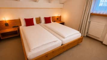 Un lit double avec une tête de lit en bois, deux tables de chevet avec des lampes, un radiateur et une fenêtre avec des rideaux.