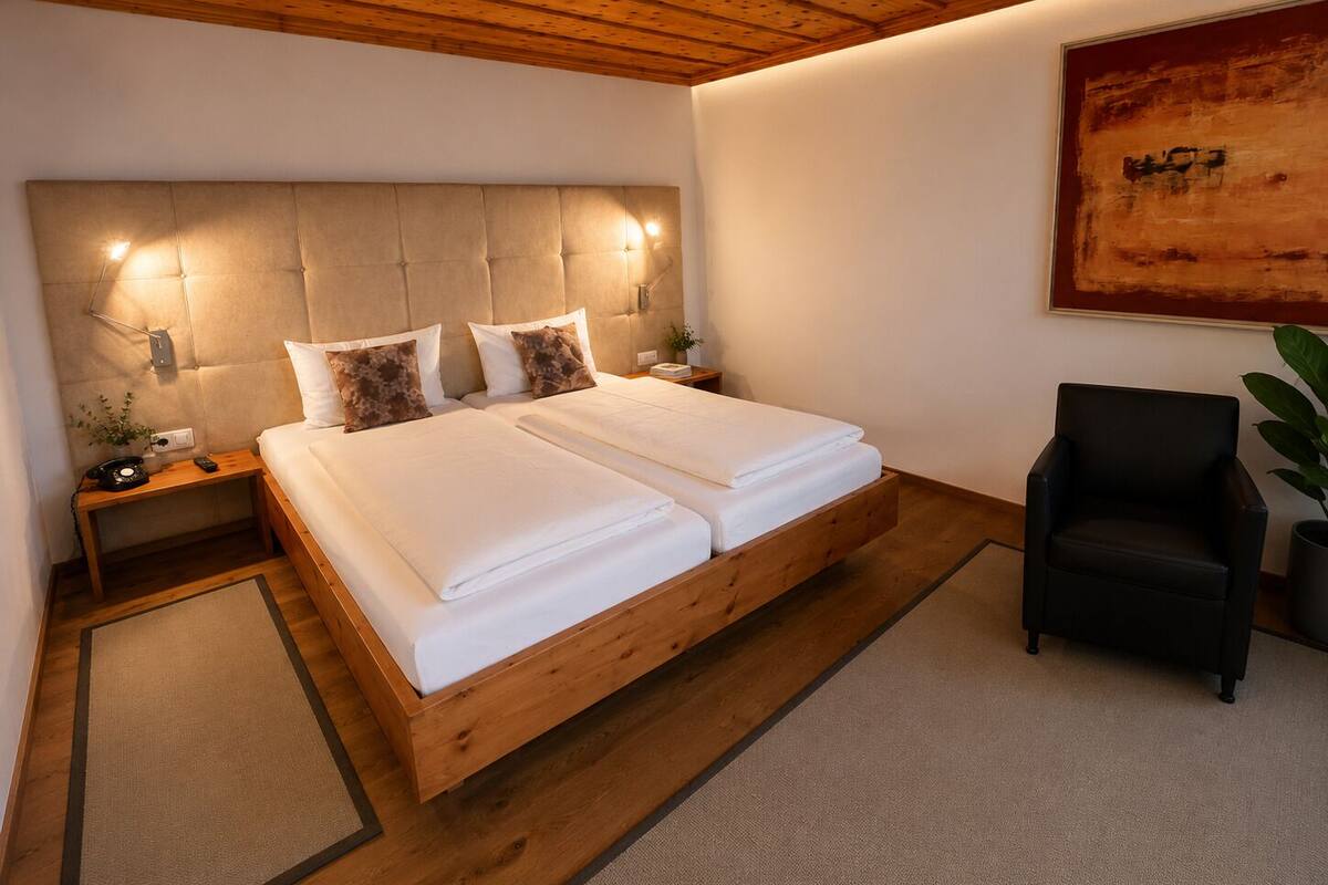 Une chambre à coucher avec un lit en bois, deux tables de chevet, une chaise et un tableau accroché au mur.