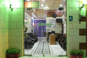 Zona de recepción con mostrador de check-in, área de asientos y tablón de anuncios.