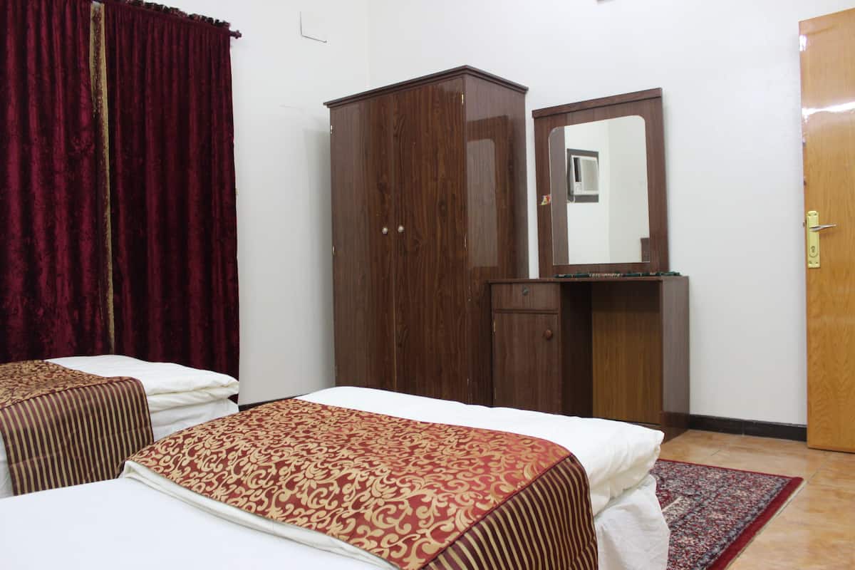 Een hotelkamer met twee bedden, een kledingkast, een spiegel en een deur.