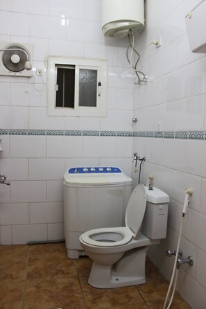 Un baño con inodoro, bidé y una ventana pequeña.