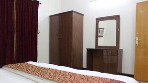 Une chambre à coucher avec un lit, une armoire, un miroir et une porte.