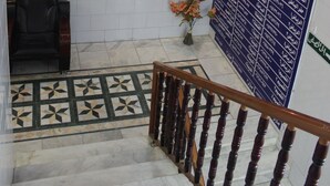 Un escalier avec une rampe en bois, un mur orné d’un panneau d’information bleu et une fresque représentant des cascades.