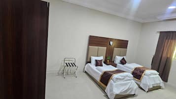 A hotel room with two beds, a small chair, and a window with curtains.