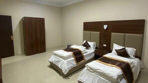 A hotel room with two beds, a wardrobe, and a door.