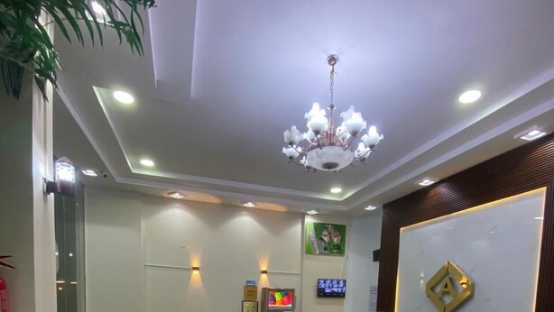 A modern lobby with a reception desk, seating area, and a chandelier.