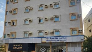A multi-story building with a flat facade, several windows, and a ground-level entrance with a sign.