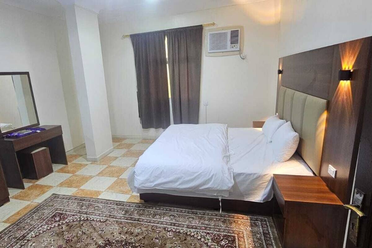 Ein Schlafzimmer mit Bett, Schminktisch, Spiegel, Teppich und Klimaanlage.