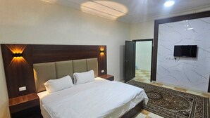 A hotel room with a bed, nightstands, a wall-mounted TV, and a marble-patterned wall.