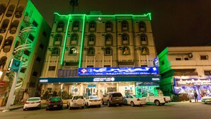 A hotel with multiple floors, a central entrance, and a parking lot with several cars.